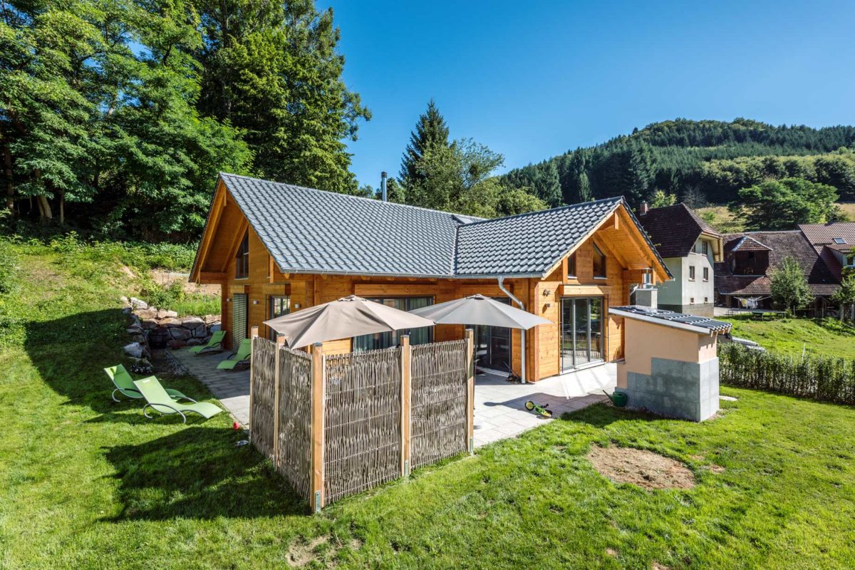 Haus Elzruhe - Eine Gruppe von Gartenstühlen sitzt auf einer üppigen grünen Wiese - Holzhaus