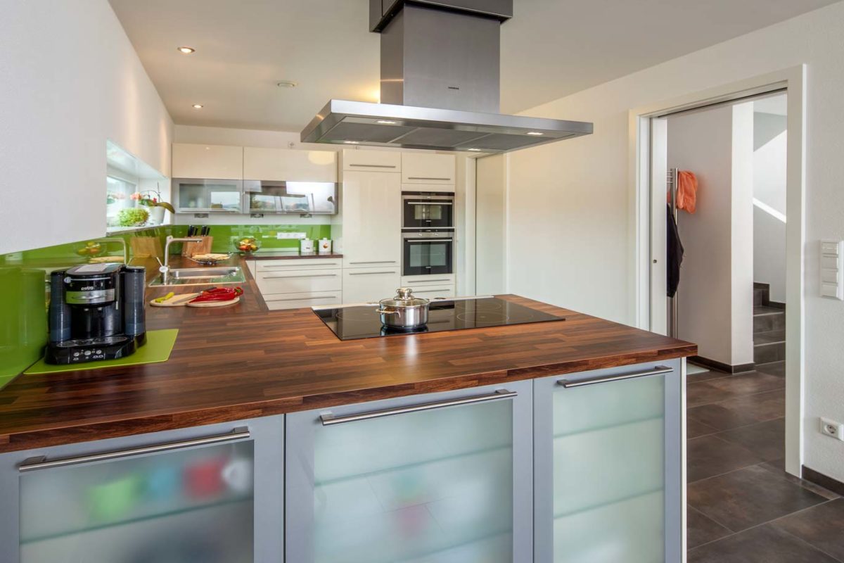 Haus Heuberger - Eine moderne Küche mit Edelstahlgeräten und Holzschränken - Haus
