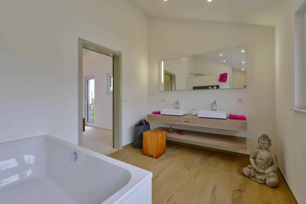 Musterhaus Vitalis - Eine große weiße Wanne neben einem Waschbecken - Bad