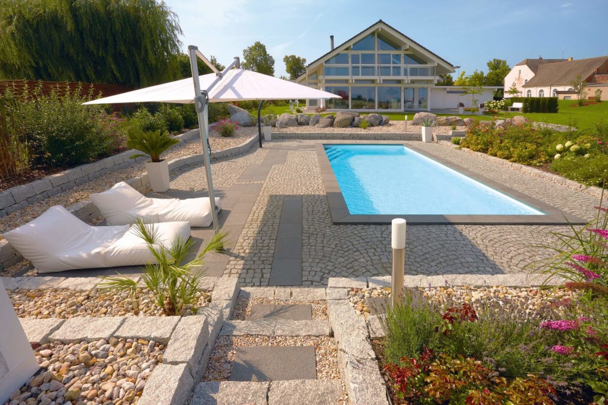 HUF HAUS Art 4 - Ein paar Liegestühle sitzen auf einer grasbewachsenen Wiese - Schwimmbad