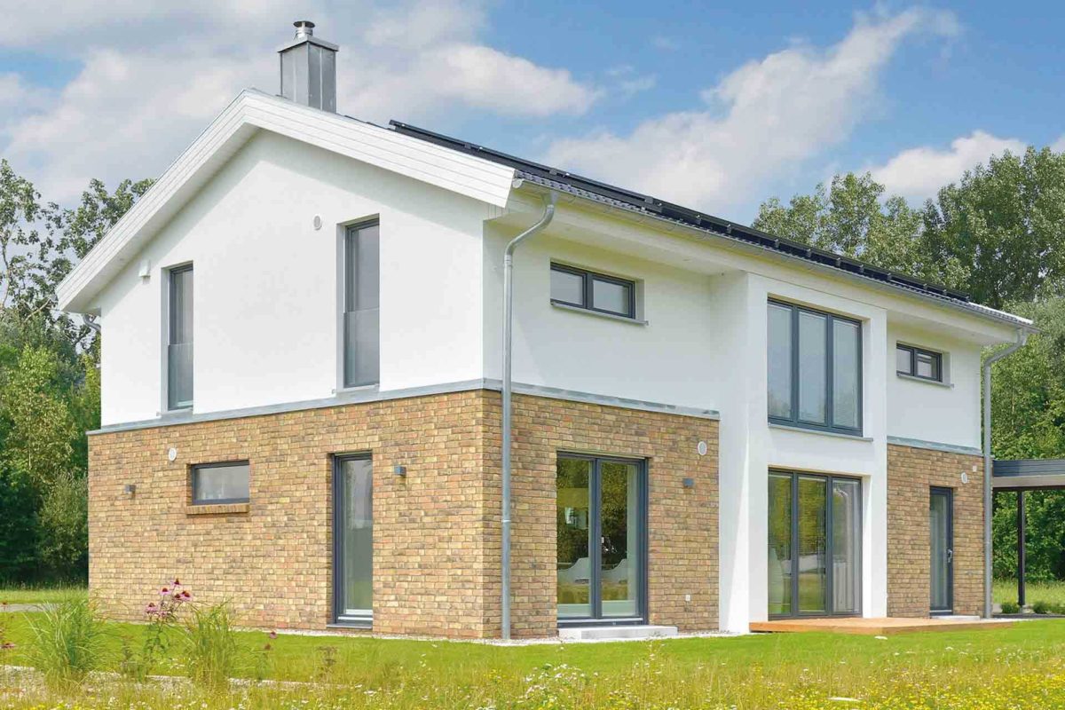 Musterhaus Kronhagen - Ein großes Backsteingebäude mit Gras vor einem Haus - Danhaus GmbH