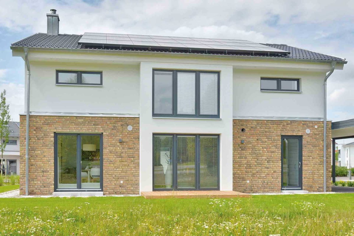 Musterhaus Kronhagen - Ein großes Backsteingebäude mit Gras vor einem Haus - Haus