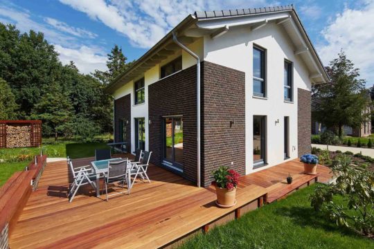 Musterhaus Melanie - Ein großes Backsteingebäude mit Gras vor einem Haus - Haus