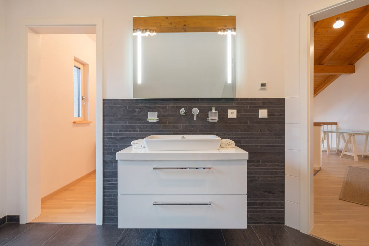 Musterhaus Tegernsee - Eine küche mit waschbecken und spiegel - Badezimmerschrank