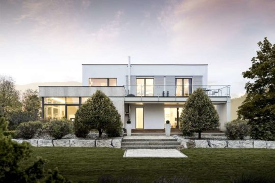 Musterhaus Box - Ein Haus mit Bäumen im Hintergrund - GRIFFNER HAUS Deutschland