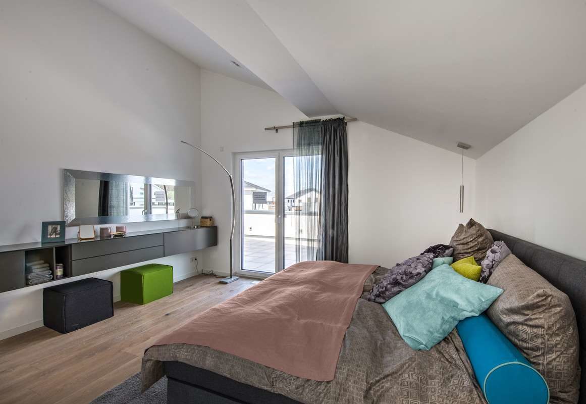 Musterhaus Günzburg - Ein Schlafzimmer mit einem großen Bett in einem Raum - Die Architektur