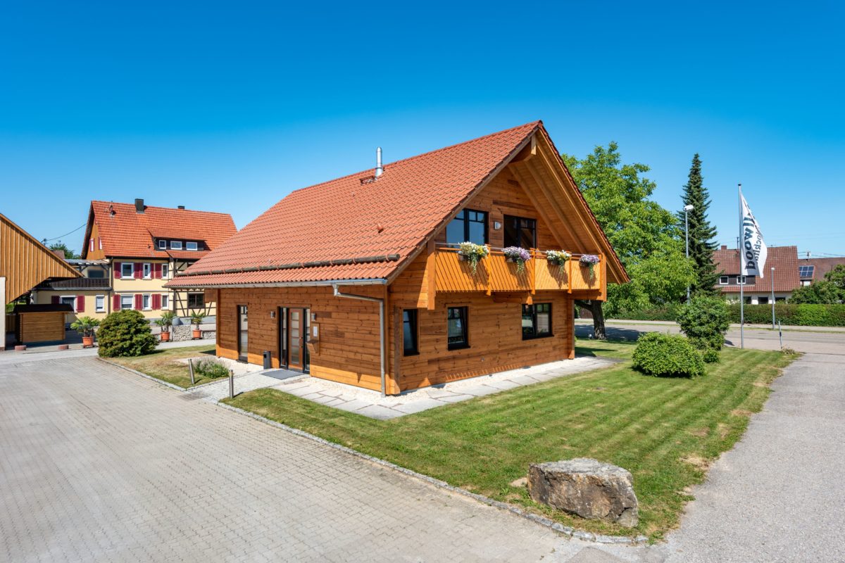 Musterhaus Hohenlohe - Ein großes Backsteingebäude mit Gras vor einem Haus - Hütte