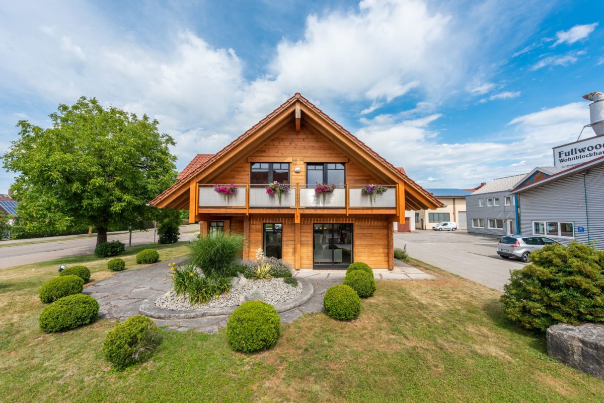 Musterhaus Hohenlohe - Ein haus mit büschen vor einem gebäude - Grundstück