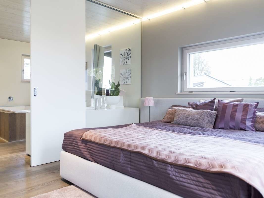 Musterhaus Box - Ein Schlafzimmer mit einem großen Bett in einem Raum - GRIFFNER HAUS Deutschland