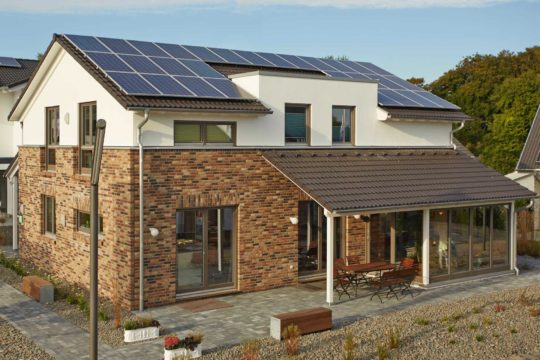 Plus-Energiehaus Isabella - Ein Haus, das an der Seite eines Gebäudes geparkt ist - Gussek Haus