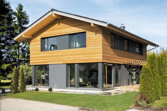 Musterhaus Poing - Ein großes Backsteingebäude mit Gras vor einem Haus - Haus