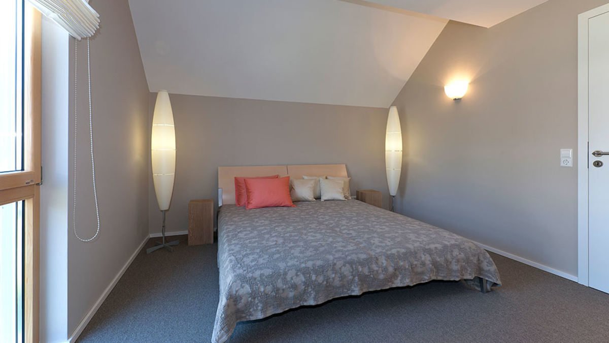 Musterhaus Fellbach - Ein Schlafzimmer mit einem Bett und einem Schreibtisch in einem kleinen Raum - Musterhaus