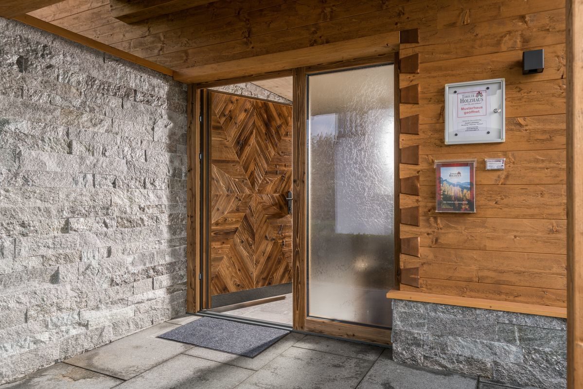 Musterhaus Poing - Eine Nahaufnahme von einem Steingebäude, das ein Schild an der Wand hat - Tiroler Holzhaus