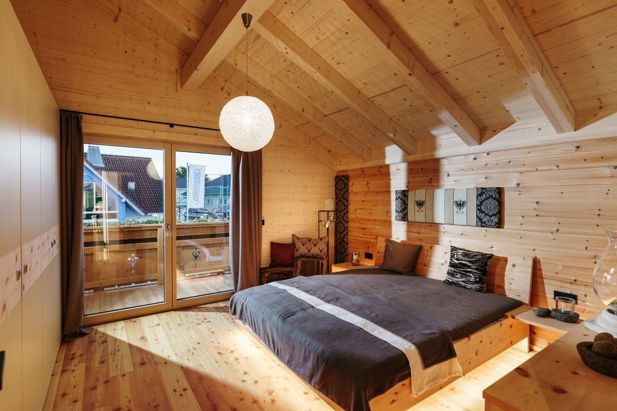 Musterhaus Poing - Ein großes Bett in einem Raum - Tiroler Holzhaus