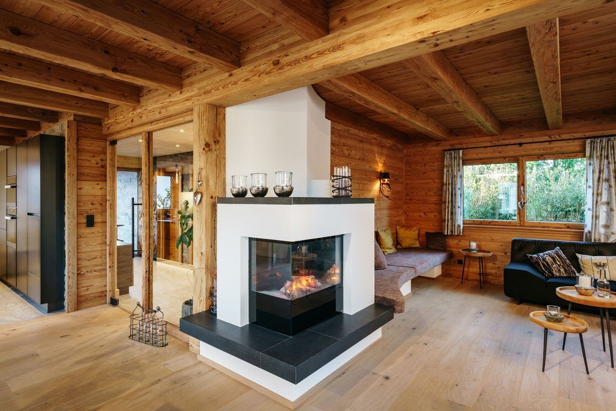 Musterhaus Poing - Ein Kamin in einem Wohnzimmer mit Möbeln und einem Kamin - Tiroler Holzhaus