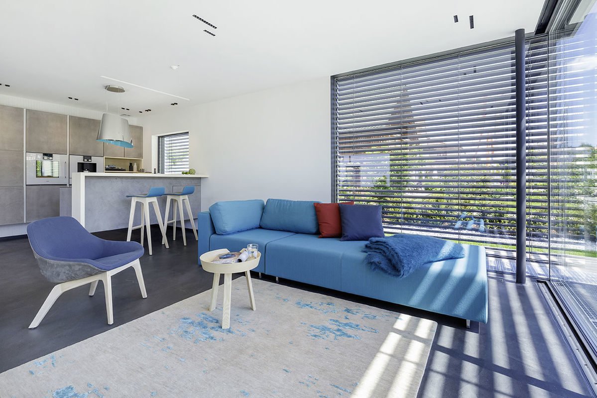 Musterhaus Fine - Ein Wohnzimmer mit Möbeln und einem blauen Stuhl - Interior Design Services