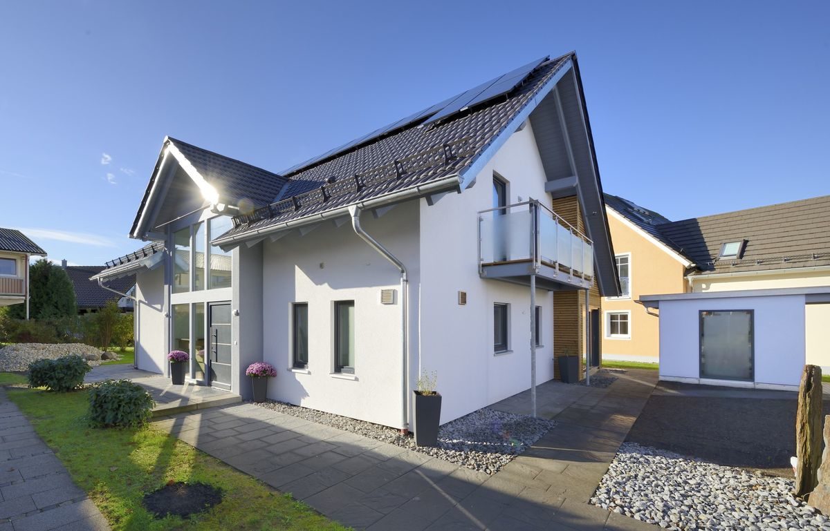 Musterhaus Poing-Grub - Ein großes Backsteingebäude mit Gras vor einem Haus - Haus