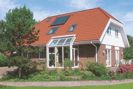 Glücksburg – Das 1Liter-Haus - Ein großes Backsteingebäude mit Gras vor einem Haus - Danhaus GmbH