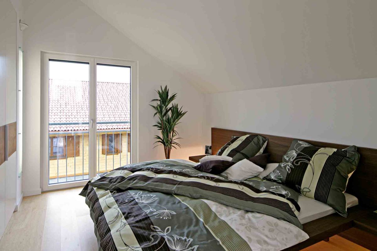 Musterhaus Erlangen - Ein Schlafzimmer mit einem großen Bett in einem Raum - Fertighaus Weiss