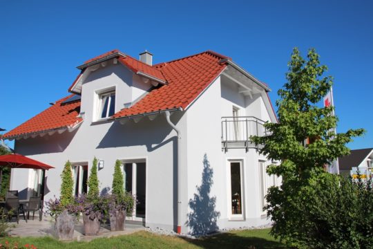 Massivhaus Poing - Ein Haus mit Bäumen im Hintergrund - MVS Ziegelbau GmbH