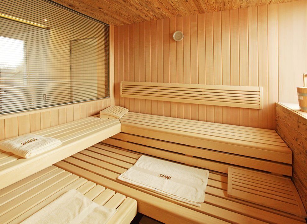 Cubus München - Eine Holzbank sitzt neben einem Kamin - Sauna