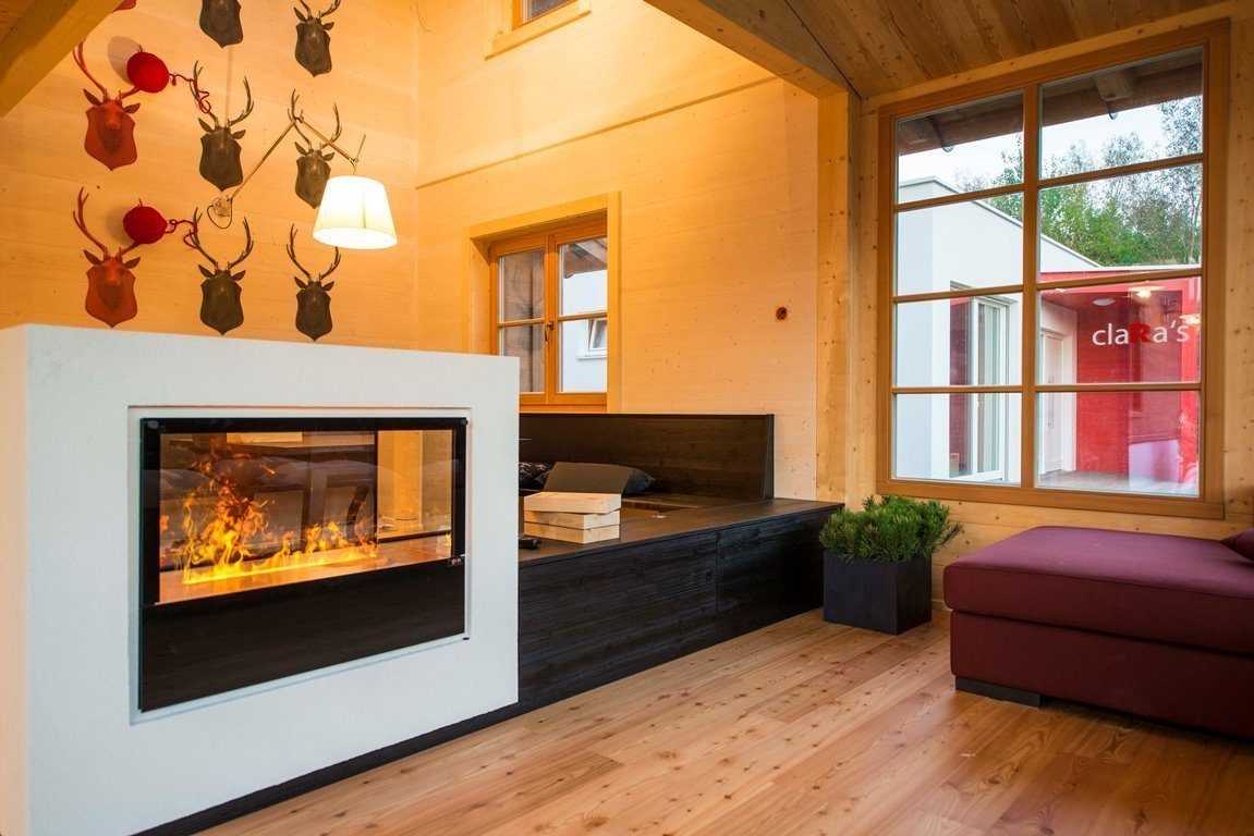 Clara - Ein Wohnzimmer mit Kamin und großem Fenster - Interior Design Services