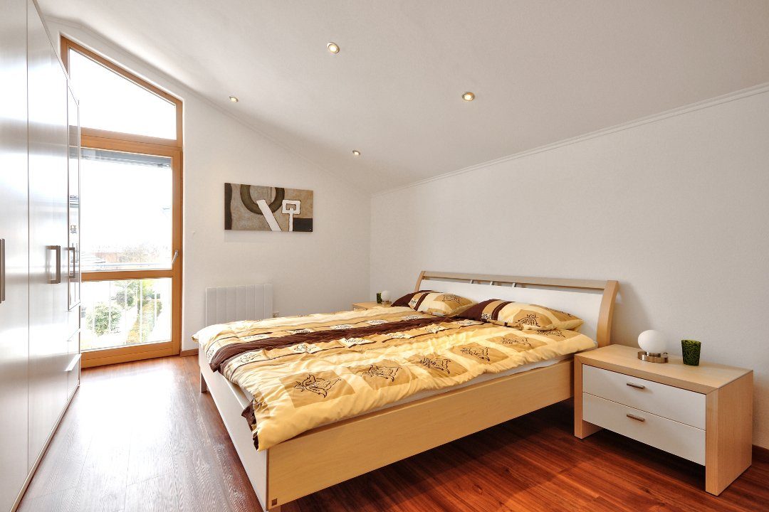 Musterhaus Poing - Ein Schlafzimmer mit einem Bett und einem Schreibtisch in einem Raum - Interior Design Services