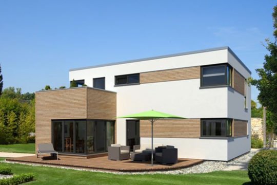 Kubus Edition Holz 65 - Ein großes Backsteingebäude mit Gras vor einem Haus - Würfelhaus
