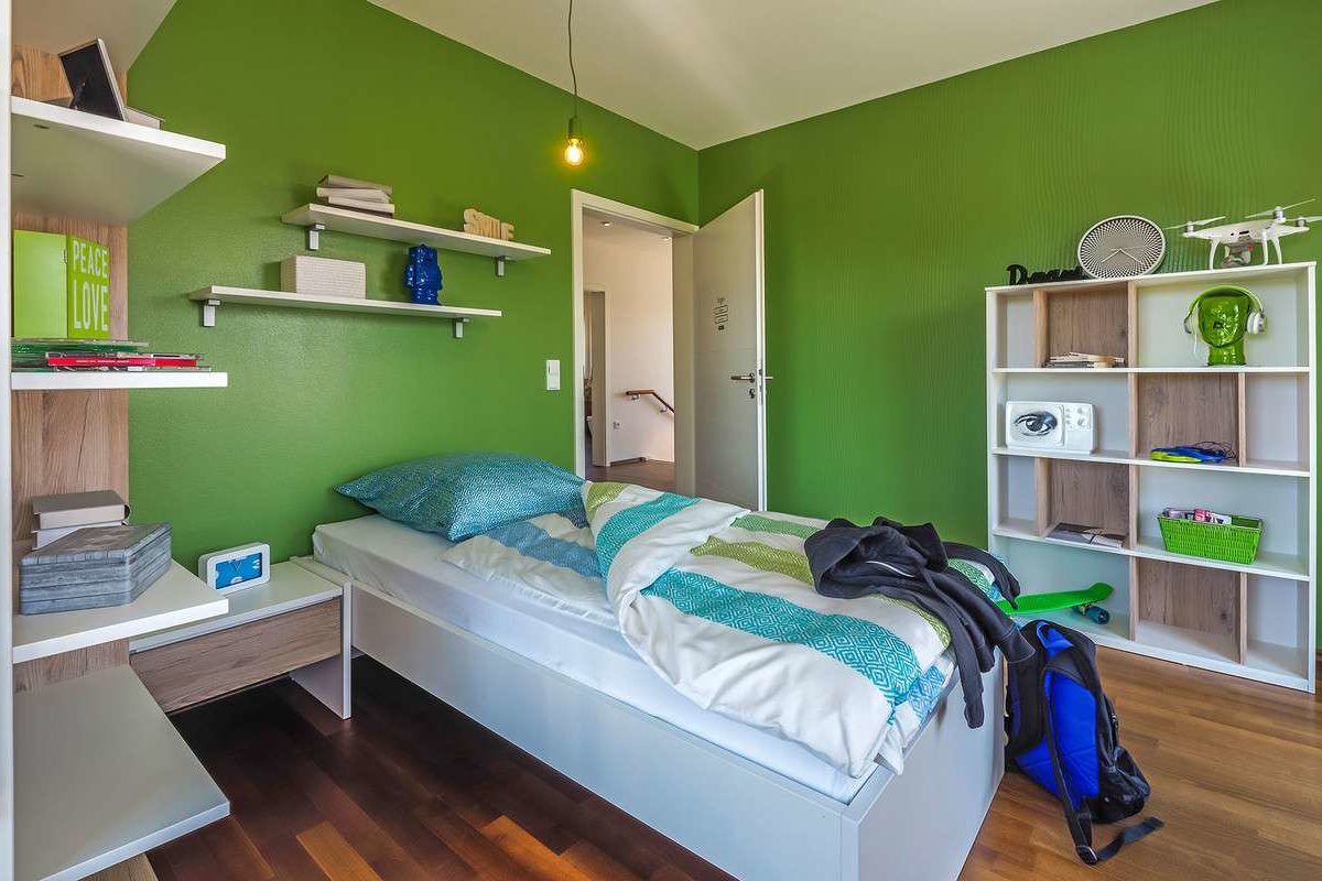 Musterhaus Falkenberg 150 - Ein Schlafzimmer mit einem Bett und einem Schreibtisch in einem Raum - Schlafzimmer