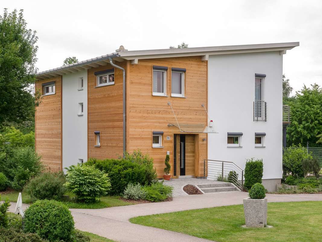 Musterhaus Falkenberg 168 - Ein großes Backsteingebäude mit Gras vor einem Haus - Fertighaus