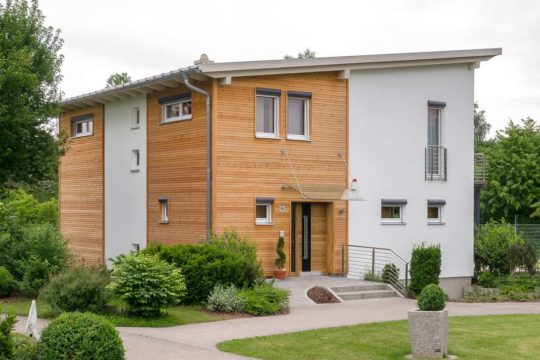 Musterhaus Falkenberg 168 - Ein großes Backsteingebäude mit Gras vor einem Haus - Fertighaus