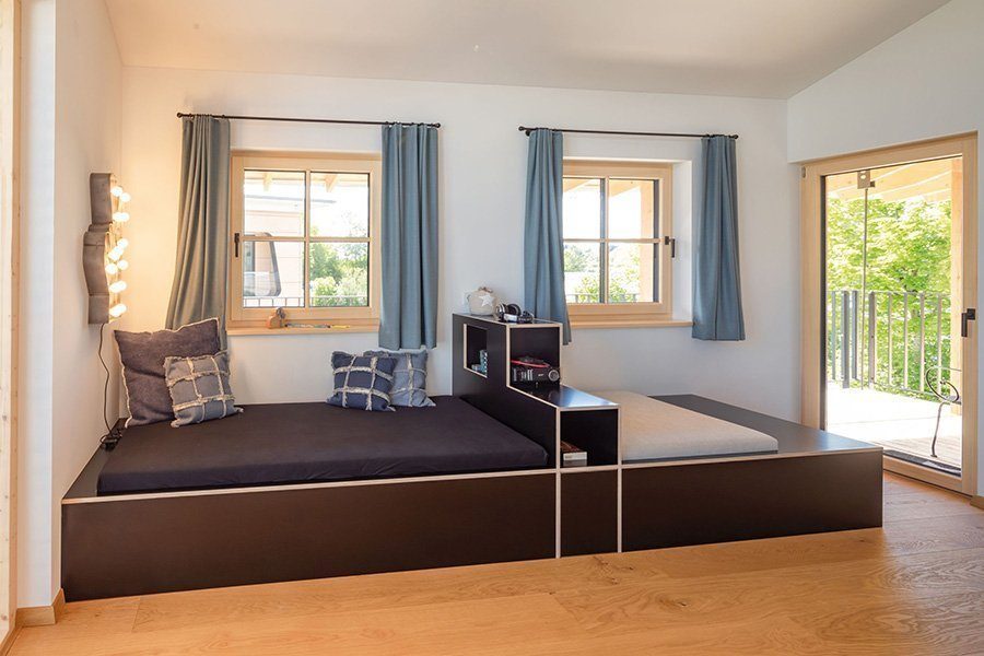 Musterhaus Liesl - Ein Wohnzimmer mit Möbeln und einem großen Fenster - Regnauer Fertigbau GmbH & Co. KG