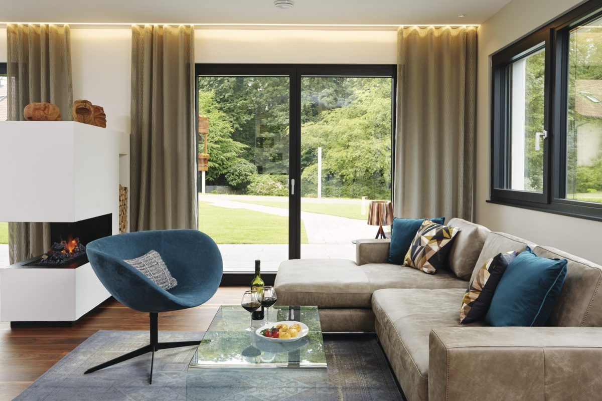 Musterhaus im Erlenpark - Eine Ansicht eines mit Möbeln gefüllten Wohnzimmers und eines großen Fensters - Welt des Lebens