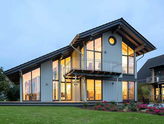 Musterhaus Bambus - Ein großes Backsteingebäude mit einer Uhr an der Vorderseite eines Hauses - Holzhaus