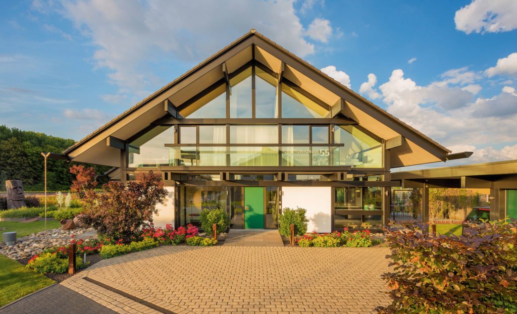 HUF HAUS Musterhaus Köln - Ein großes Backsteingebäude mit Gras vor einem Haus - HUF HAUS Musterhaus Köln