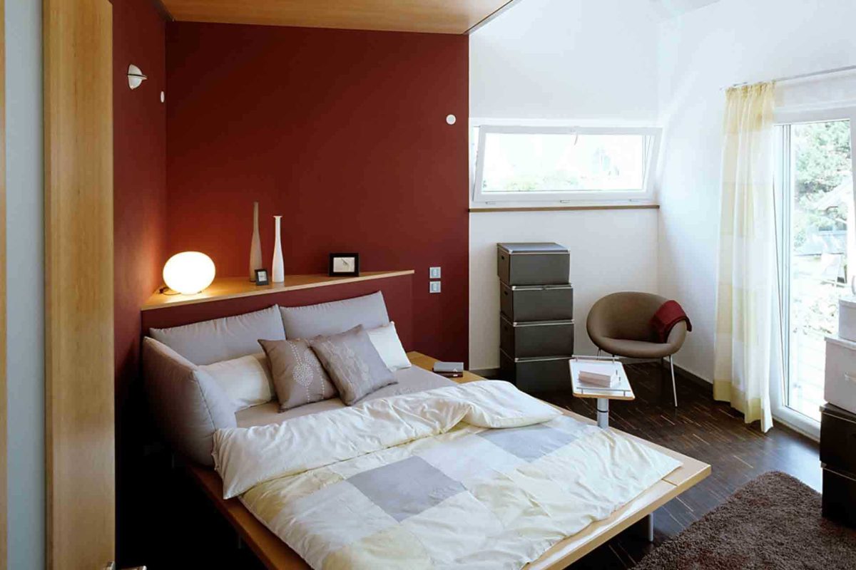 Musterhaus Mannheim - Ein Schlafzimmer mit einem Bett und einem Stuhl in einem Raum - Schlafzimmer