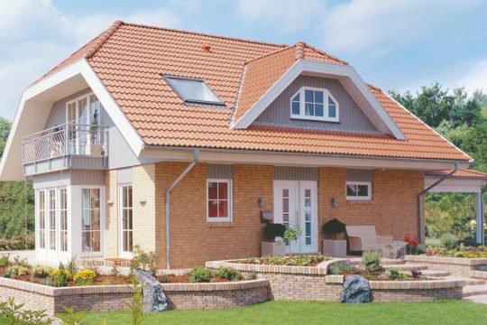 Automatisch gespeicherter Entwurf - Ein großes Backsteingebäude mit Gras vor einem Haus - Fertighaus