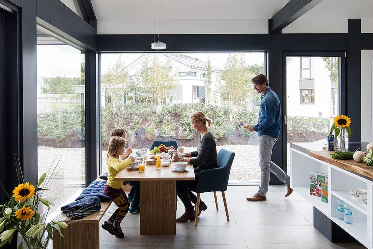 Musterhaus Günzburg - Eine Person, die an einem Tisch vor einem Fenster sitzt - Haus