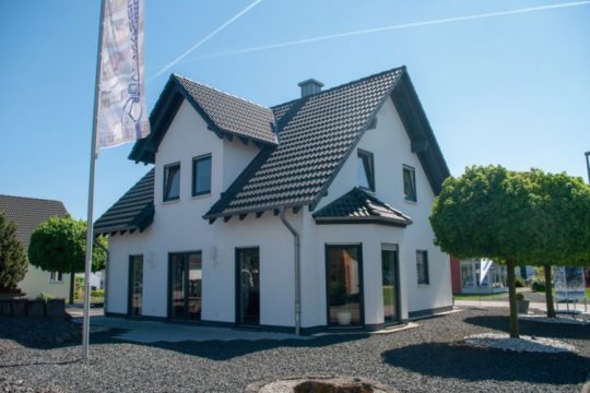 Automatisch gespeicherter Entwurf - Ein Baum vor einem Haus mit Amelia Earhart Birthplace im Hintergrund - Massivhaus Mittelrhein - Musterhaus Mülheim-Kärlich