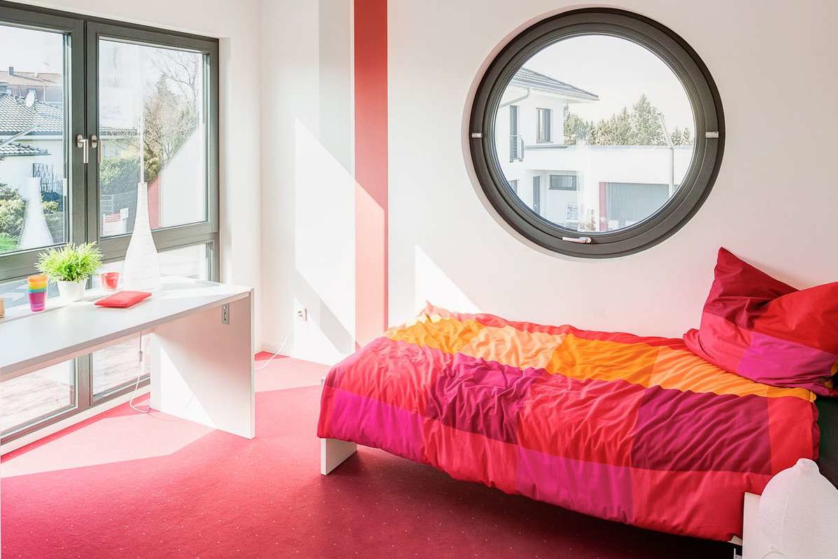 Musterhaus Wuppertal - Ein Schlafzimmer mit einem großen roten Stuhl in einem Raum - Bettrahmen