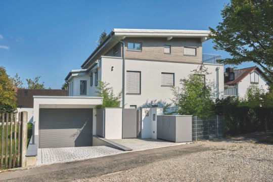 Kundenhaus Brunnthal - Ein Haus mit Bäumen im Hintergrund - Mehrfamilienhaus