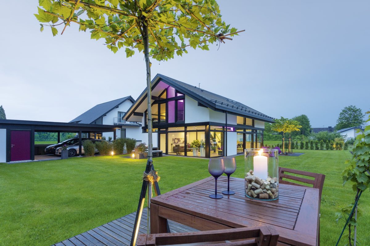 HUF HAUS MODUM 7 - Ein paar Liegestühle sitzen auf einer grasbewachsenen Wiese - Huf Haus