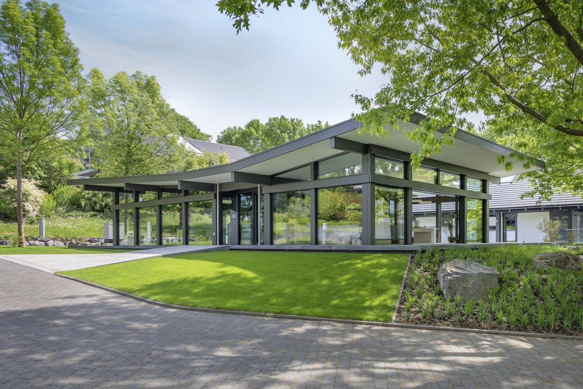 Musterhaus ART Bungalow - Ein Haus mit Bäumen im Hintergrund - Huf Haus