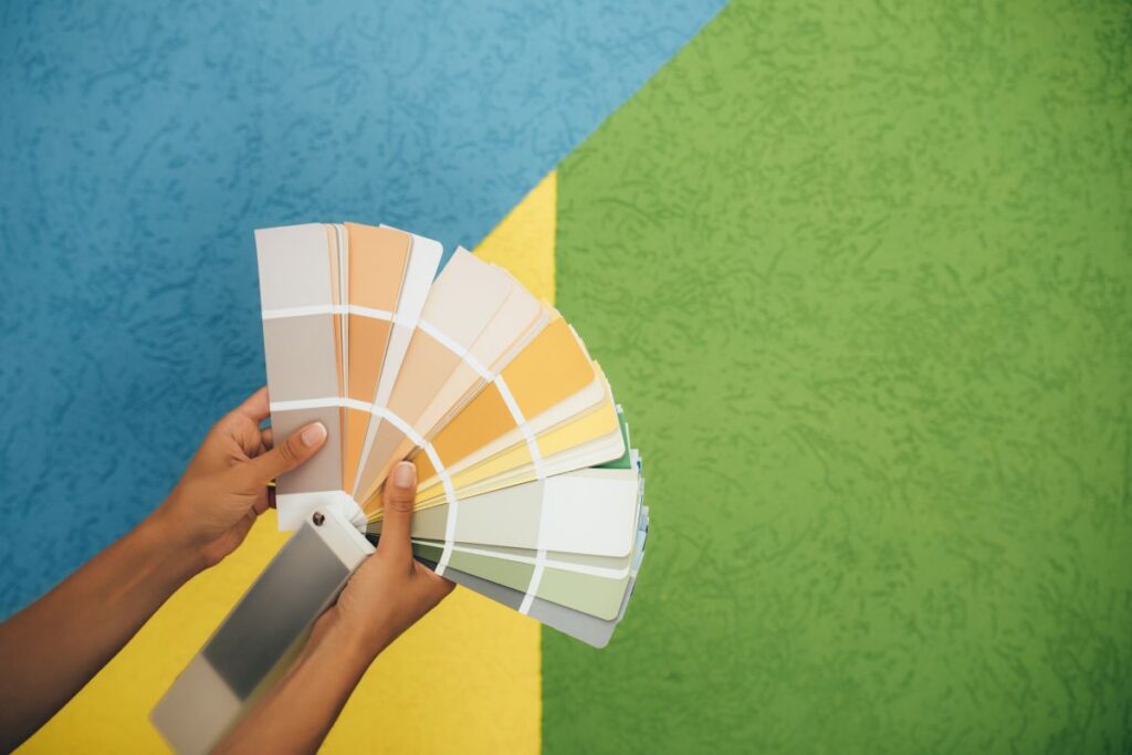 Bauleistungsbeschreibung richtig lesen Hausbau Helden Frau wählt Farbe anhand eines Musterkatalogs, der in der Nähe der Wand steht.