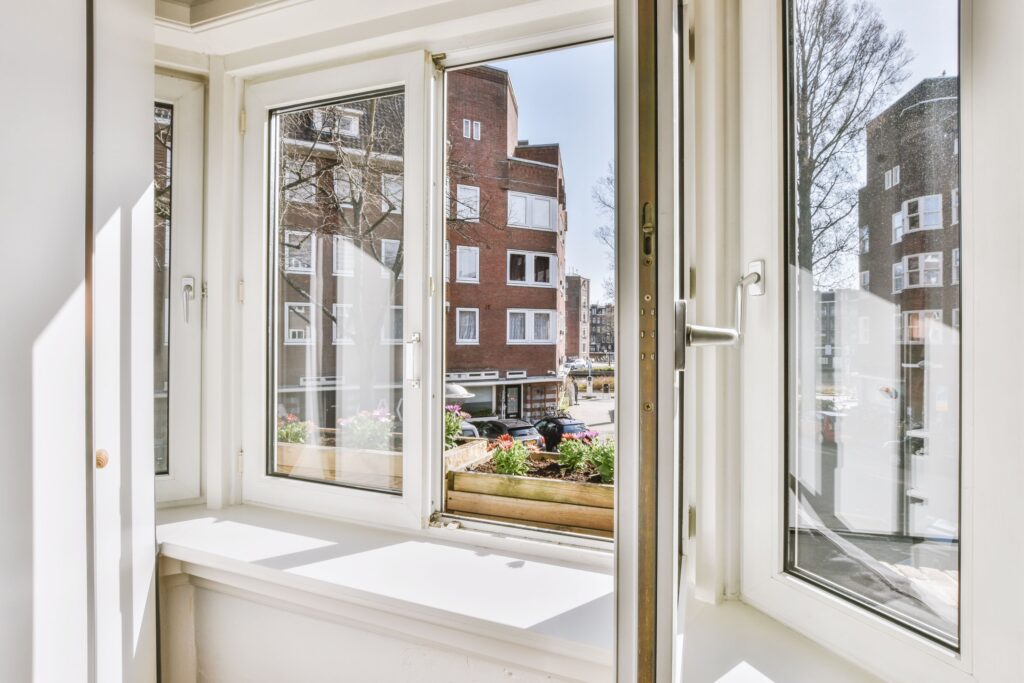 Sonnenlicht: Eigenschaften und deren Wirkung auf dein Haus Hausbau Helden Geöffnetes Fenster von der Sonne bestrahlt mit Ausblick auf Häuser.