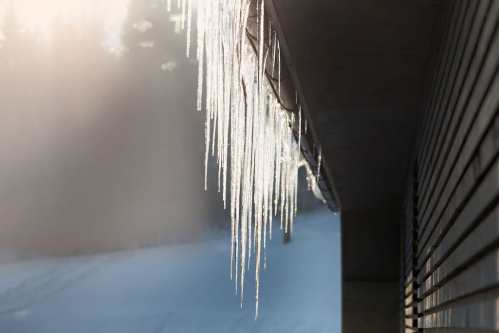 Wichtige Nebenkosten von Hausbesitzern Hausbau Helden schöne Eiszapfen auf dem Dach des Hauses an einem sonnigen Tag