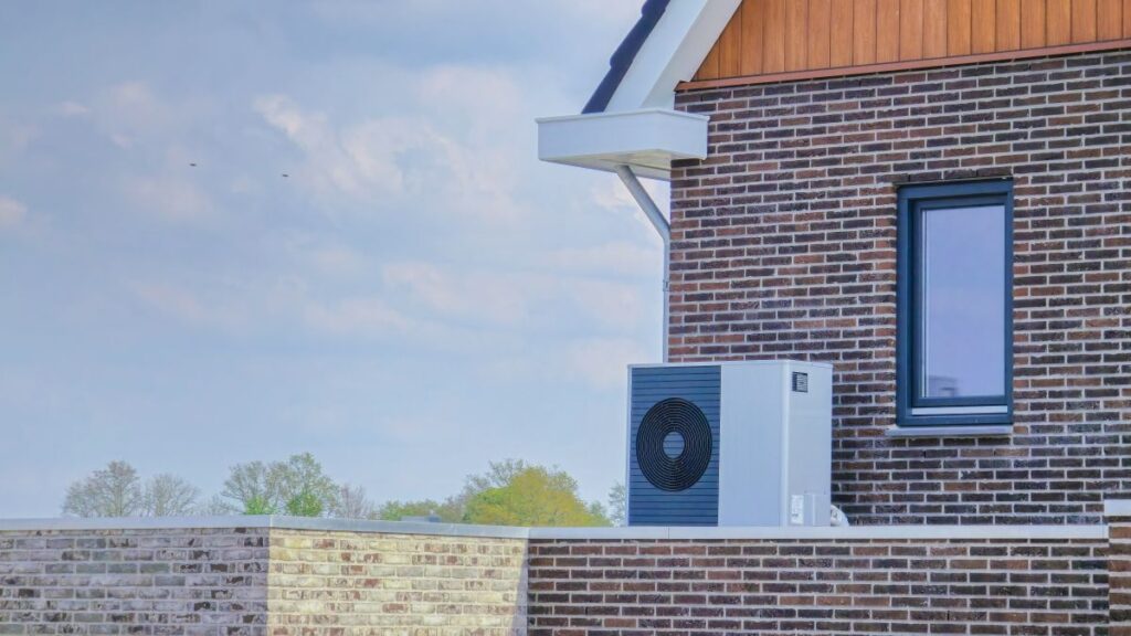 Erdwärme vs. Luftwärme: Wann ist die Erdwärmepumpe die bessere Wahl? Hausbau Helden Luftwärmepumpeneinheit, installiert im Freien in einem modernen Haus mit Ziegeln in den Niederlanden im Frühling