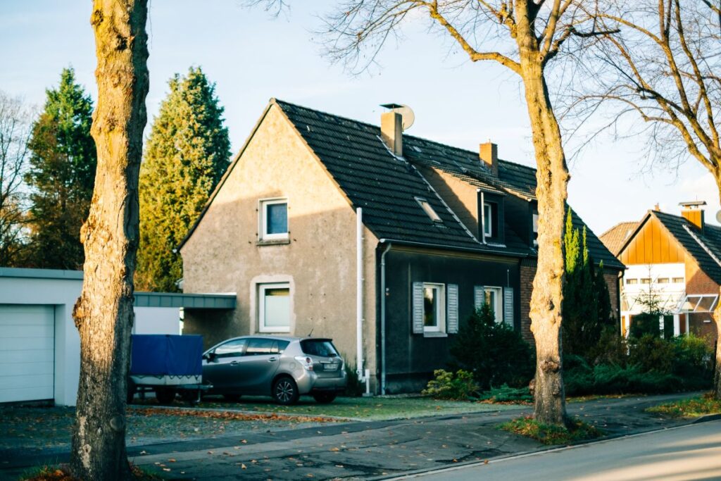 Wärmepumpe nachrüsten: Die wichtigsten Praxisschritte und Optionen im Portrait Hausbau Helden Straße und Einfamilienhaus mit altem Baumbestand und einem Auto in der Auffahrt