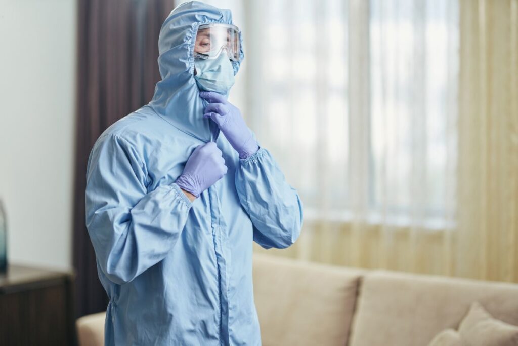 Schimmel selbst sanieren – was geht, was ist tabu? Hausbau Helden Mann mit Maske und Schutzanzug in Wohnung